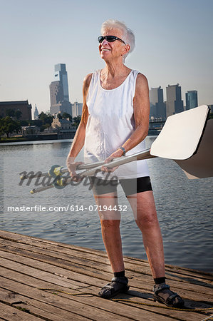 Rower on pier holding oars