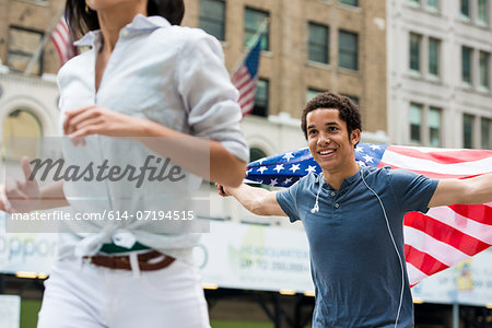 Man with American flag running after woman