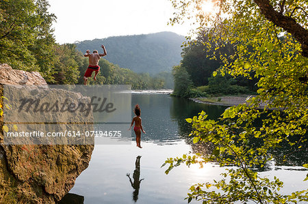 Young couple jumping from rock ledge, Hamburg, Pennsylvania, USA