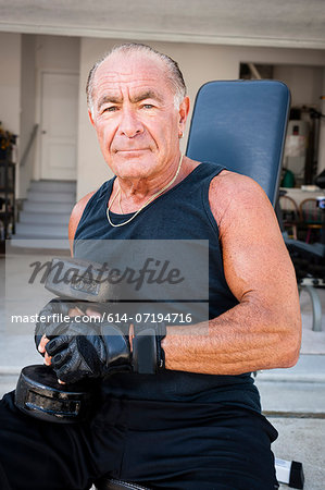 Portrait of muscular senior man holding dumb bells