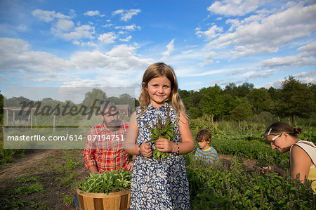 Portrait of girl holding bunch of leaves on family herb farm