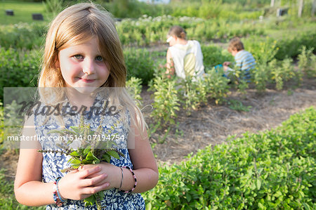 Portrait of girl holding bunch of foliage on herb farm