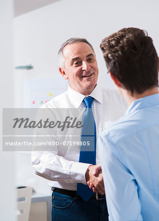 Businessman shaking hands with apprentice in office, Germany