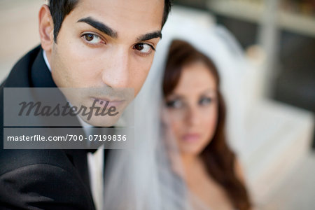 Close-up portrait of groom, with bride in the background, Ontario, Canada