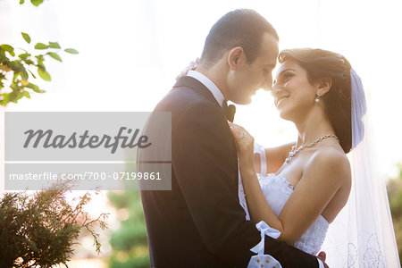Close-up portrait of bride and groom standing outdoors, face to face, smiling and embracing, Ontario, Canada Close-up portrait of bride and groom standing outdoors, face to face, smiling and embracing, Ontario, Canada