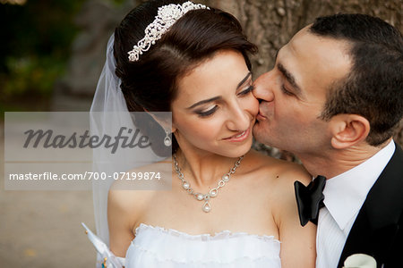 Close-up portrait of groom kissing bride on cheek, outdoors in Autumn, Ontario, Canada