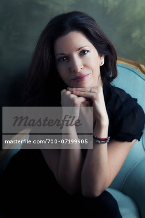 Portrait of Mature Woman sitting in Chair leaning on Hands, Studio Shot