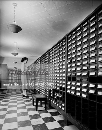 1950s 1960s TWO YOUNG WOMEN STANDING BESIDE OPEN DRAWERS OF COMPUTER PUNCH CARD FILING CABINETS