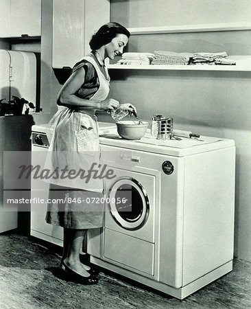 1950s  HOUSEWIFE USING TOP OF WASHING MACHINE AND DRYER AS KITCHEN COUNTER