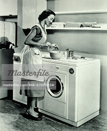 1950s HOUSEWIFE USING TOP OF WASHING MACHINE AND DRYER AS KITCHEN COUNTER 1950s HOUSEWIFE USING TOP OF WASHING MACHINE AND DRYER AS KITCHEN COUNTER