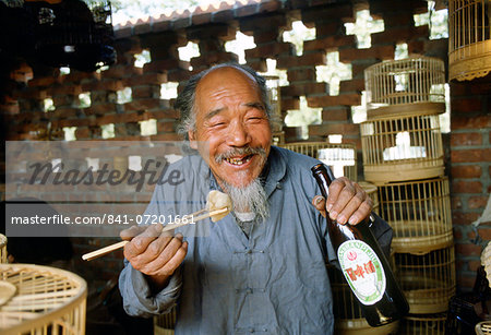 Man eating with chopsticks & drinking beer, Beijng, China