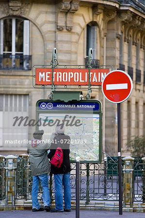 Tourists on foot study Metropolitain subway map for the Paris Metro in Rue du Bac, Left Bank, Paris, France