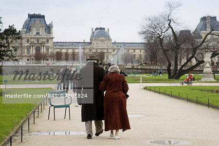 Elderly couple take a calm stroll arm in arm through Jardin des Tuileries by the Louvre Museum art gallery, Central Paris, France Elderly couple take a calm stroll arm in arm through Jardin des Tuileries by the Louvre Museum art gallery, Central Paris, France