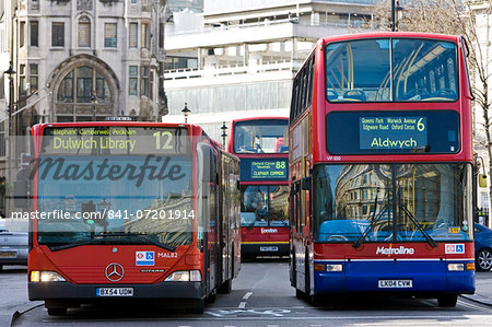 Public transport buses travel in heavy traffic in Trafalgar Square, London city centre, England, United Kingdom