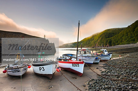 Fishing vessels beached at low tide in Clovelly harbour, Devon, England, United Kingdom, Europe