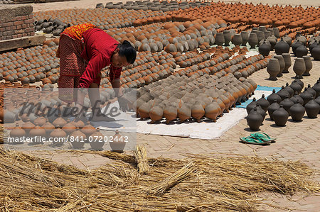Woman turning pots to dry in sunshine, Potter's Square, Bhaktapur, Nepal, Asia