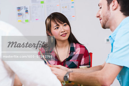 Close-up of three young business people meeting and discussing in office, Germany