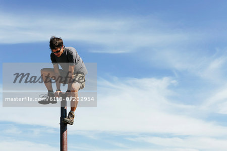 Man climbing on to the top of a metal post, on Surprise Mountain, Alpine Lakes Wilderness, Mount Baker-Snoqualmie National forest. Man climbing on to the top of a metal post, on Surprise Mountain, Alpine Lakes Wilderness, Mount Baker-Snoqualmie National forest.