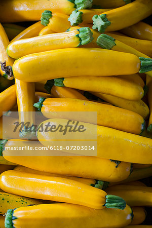 Organic vegetables on a farm stand. Piles of fresh courgettes.