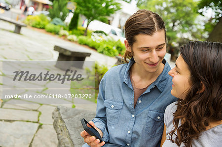 A young couple side by side, flirting and taking photographs.