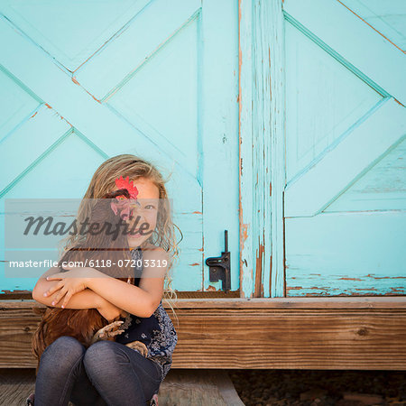 A young girl holding a chicken in her arms.