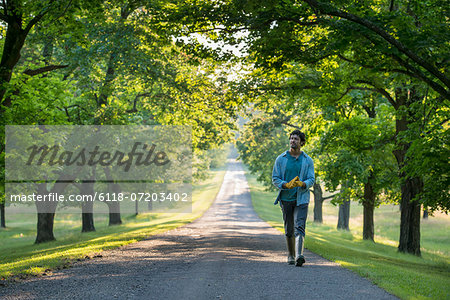 A man walking down a tree lined path.