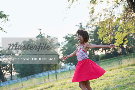 A woman in a red skirt, whirling around in the open air, with her arms outstretched.