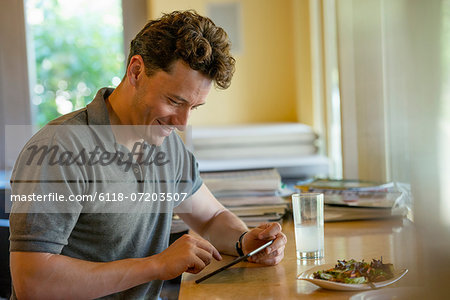 A person sitting alone in a cafe. A man using a digital tablet.