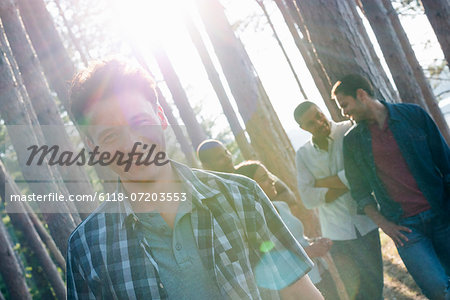 Lakeside. A group of people, friends gathered in the shade of pine trees in summer.