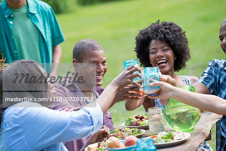 A group of adults and young people at a meal in the garden of a farmhouse.