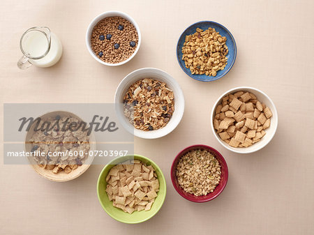 Overhead view of bowls of a variety of healthy cereals and jug of milk, studio shot