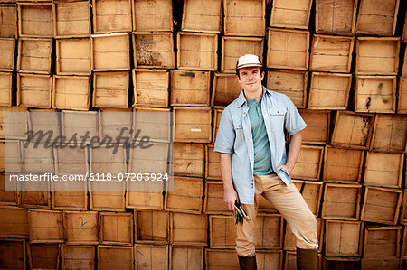 A farmer standing in front of a wall of stacked wooden crates for produce.
