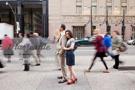 Couple standing on sidewalk on busy, city street, Toronto, Ontario, Canada