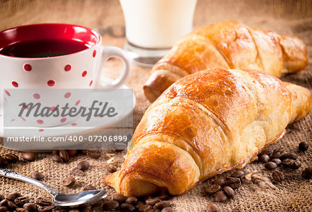 Fresh baked French croissant and dark coffee in the cup