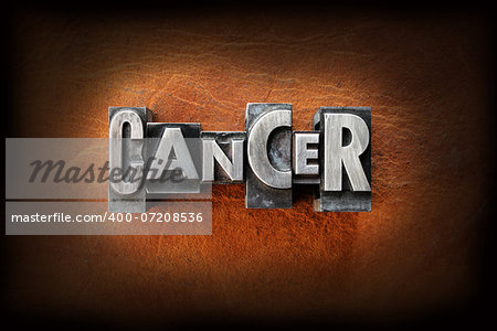 The word cancer made from vintage lead letterpress type on a leather background.
