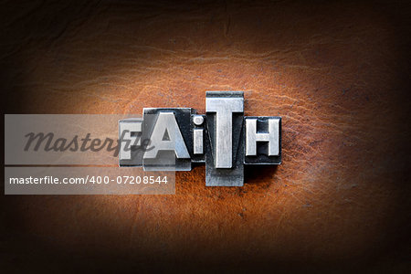 The word faith made from vintage lead letterpress type on a leather background.