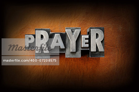 The word prayer made from vintage lead letterpress type on a leather background.