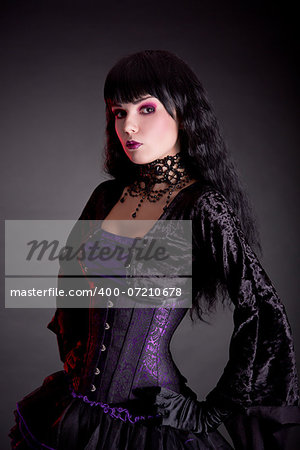 Portrait of attractive gothic girl in elegant medieval costume, studio shot on black background