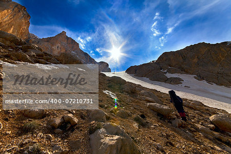 Weary hiker ascent to mountain pass in evening. Turkey, Central Taurus Mountains, Aladaglar (Anti-Taurus). Wide angle view.