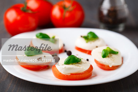 Tomato and mozzarella with basil leaves on plate