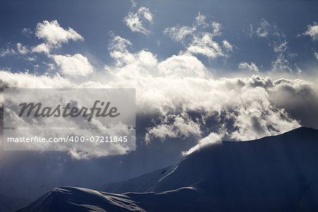 Evening mountain in haze and sunlight clouds. View from ski resort Gudauri. Caucasus Mountains, Georgia.