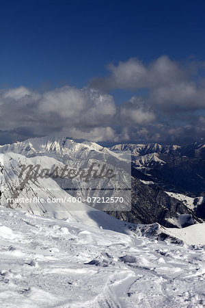 Sunlit mountains in clouds, view from off-piste slope. Caucasus Mountains, Georgia, ski resort Gudauri.