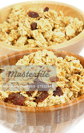 Breakfast Cereal Flakes with Slices of Nuts and Raisins closeup in Two Wooden Bowls