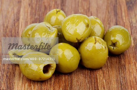 Heap of Delicious Pickled Green Olives with Spices and Olive Oil closeup on Wooden background