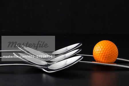 Spoons and different golf balls on a black table