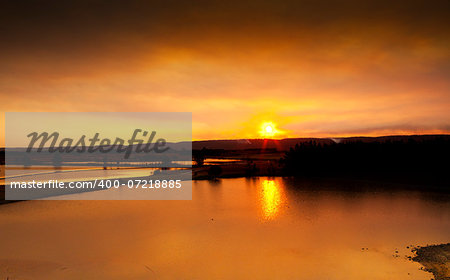 Sunset over Penrith Lakes. Ducks swim in the serene lakes as the warm golden orange sun sets behind the mountains.  Buyers, image has fine grain.