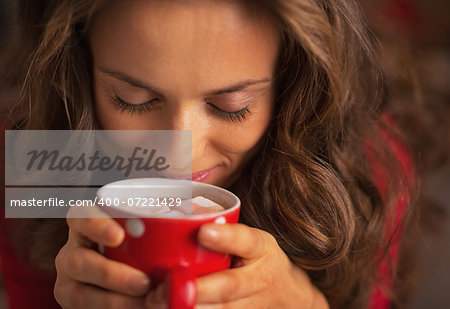 Portrait of happy young woman enjoying cup of hot chocolate with marshmallow