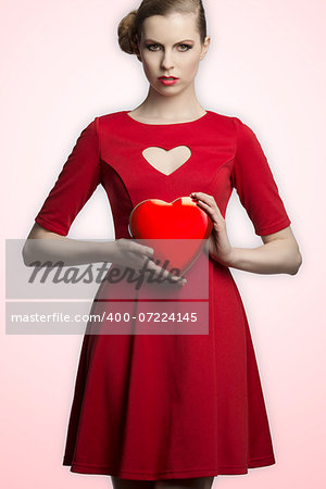 pretty blonde girl with creative hair-style and red romantic dress taking in the hands one hearth shaped box