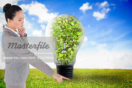 Composite image of unsmiling thinking asian businesswoman pointing