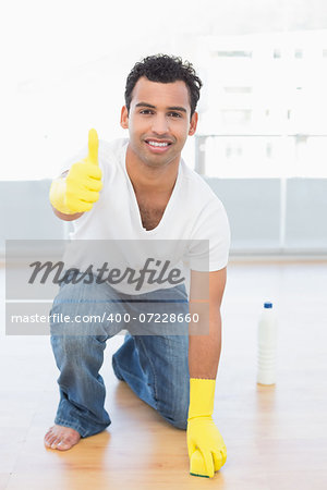 Portrait of a smiling young man cleaning the floor while gesturing okay sign at house